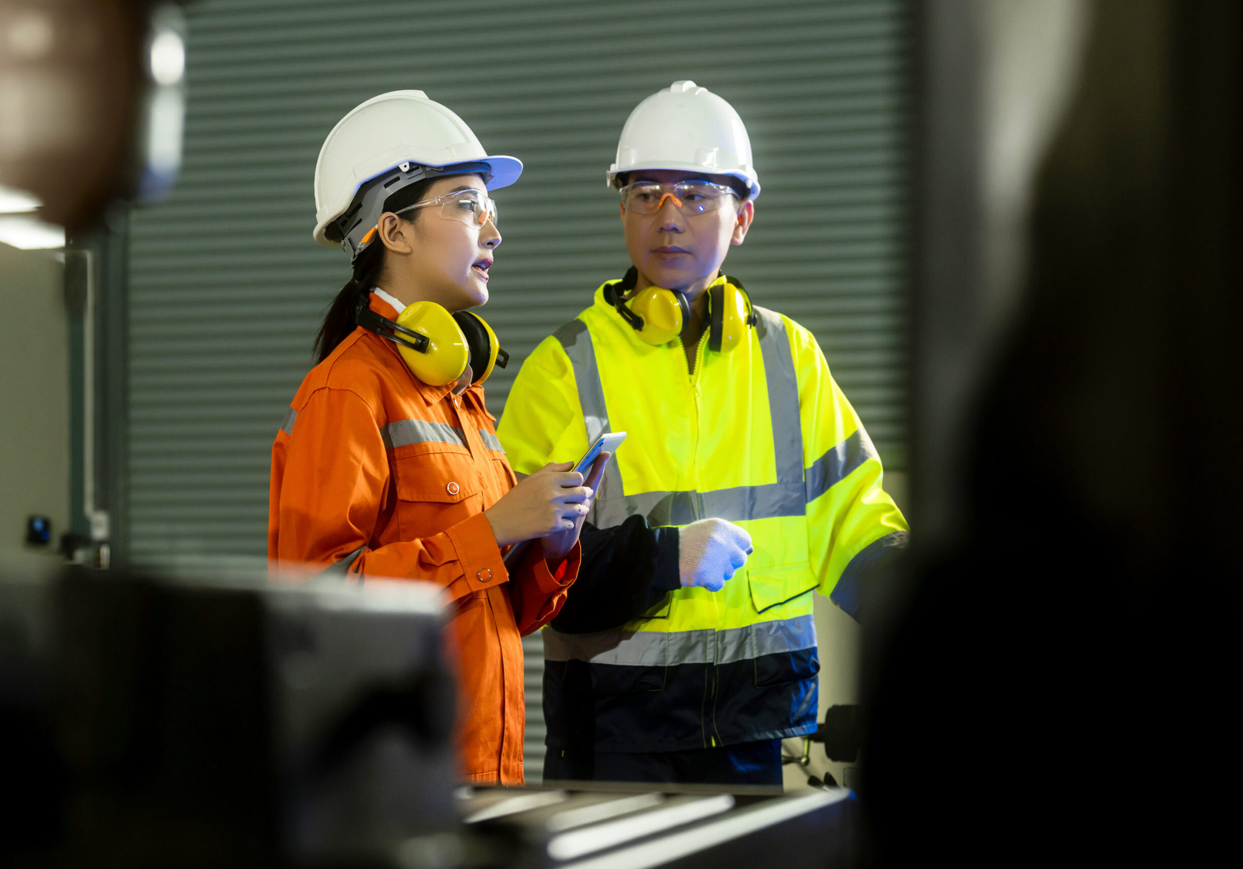 engineer cooperation Two asian maintenance engineers men and women inspect relay protection system with tablet device to control quality control process work a heavy industry manufacturing factory